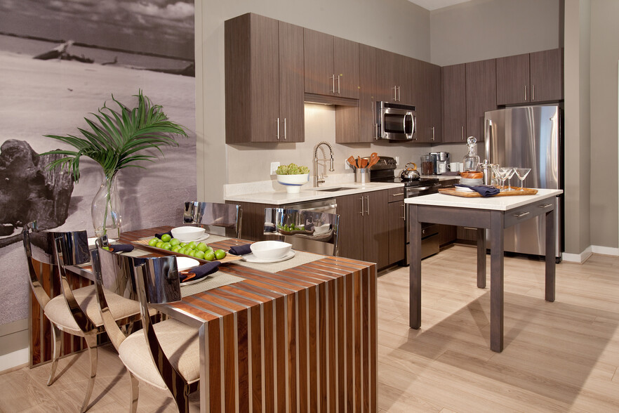 Dining area and open concept kitchen with quartz stone countertops, stainless-steel appliances, kitchen island and hard surface flooring - Avalon Potomac Yard