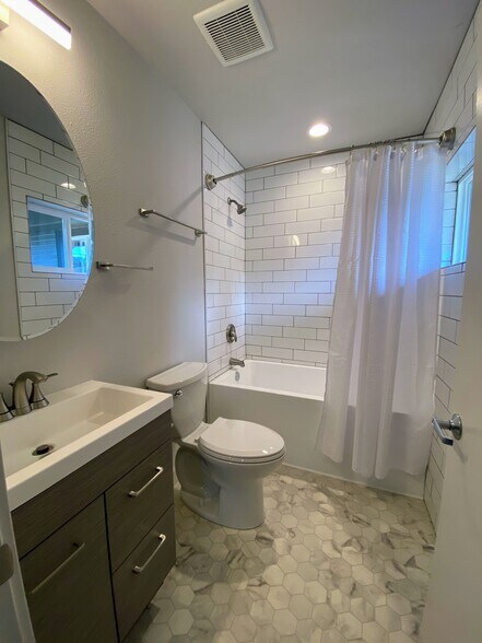 Modern bathroom with solid surface countertops, white vanity, and contemporary fixtures. - 575 Greenwood Ave