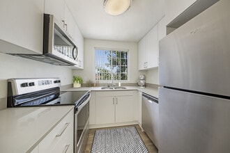Renovated Package kitchen with white cabinetry, grey quartz countertops, stainless steel appliances, upgraded lighting and fixtures, and hard surface flooring throughout kitchen, dining area, and bath. - eaves La Mesa