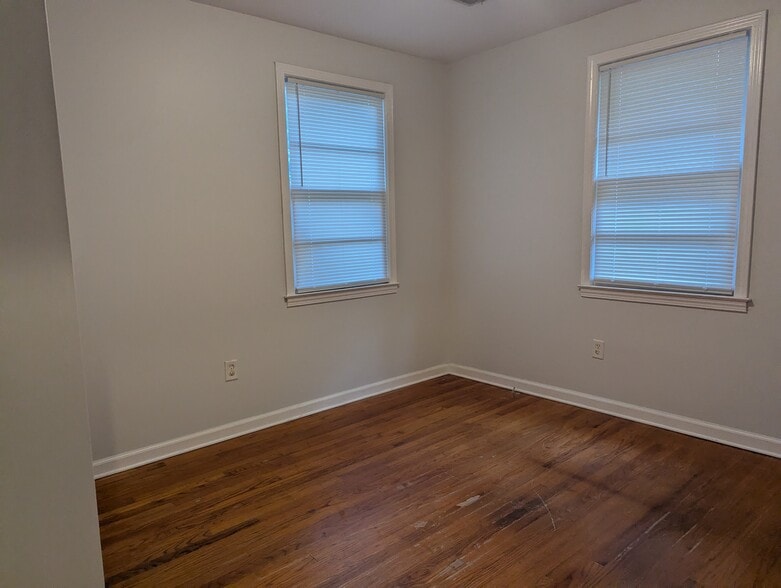 Sunlit bedroom with neutral paint, dual windows, and wood-style flooring. - 1527 Brookbank Ave