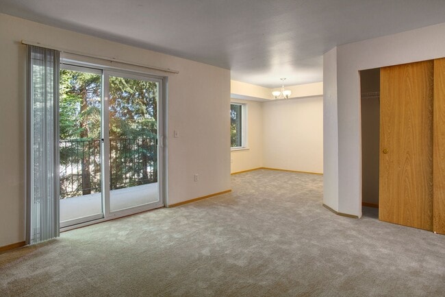 A spacious living room with sliding glass doors leading out to the balcony and a view into the dining area - Lake Park