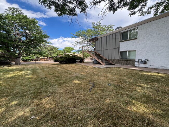 Charming apartment exterior with lush green lawn and mature trees, offering serene outdoor space and scenic views. - Copperwood Apartments