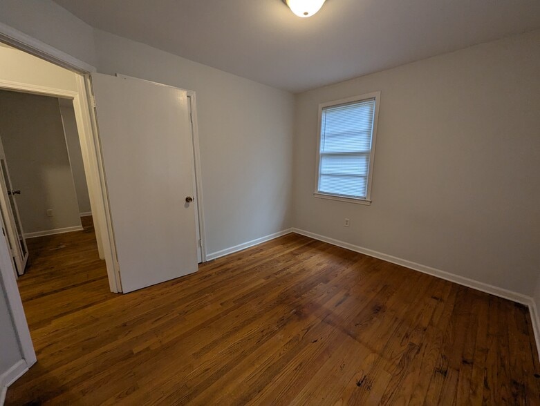 Comfortable bedroom featuring warm wood flooring and ceiling lighting. - 1527 Brookbank Ave