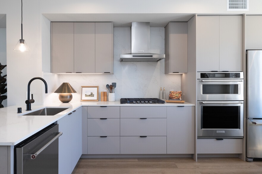 Signature Collection I 3-Bedroom Townhome Kitchen with light grey cabinetry, white marbled quartz countertops, and upgraded stainless steel appliances - Avalon Pleasanton