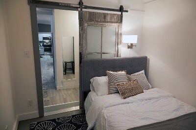 New double Sealy Posture-Pedic bed with upholstered headboard, provided linens, wall lamp and caddy. - 9 May St