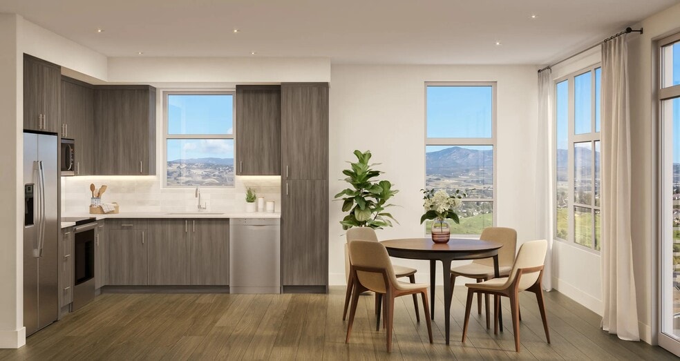 Premium kitchen and dining space with warm wood cabinetry, quartz surfaces, and expansive windows framing hillside views and natural light. - Modera Melrose
