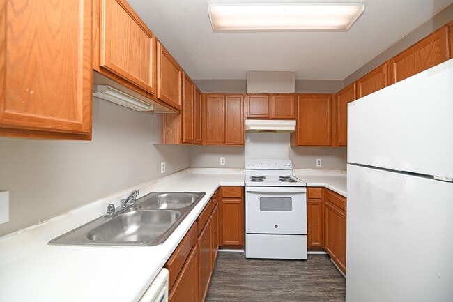 Kitchen with white appliances, wooden cabinetry, and ample counterspace - Prairie Creek Estates