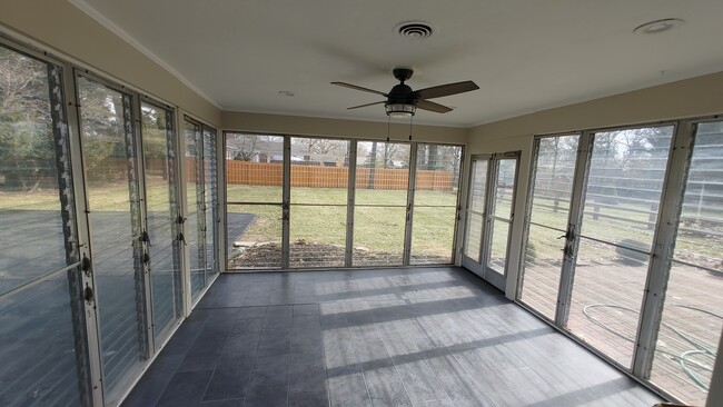 Large sunroom area w/ new tile floor, ceiling fan, double door exit to patio and exit to garage area - 6934 Winding Way