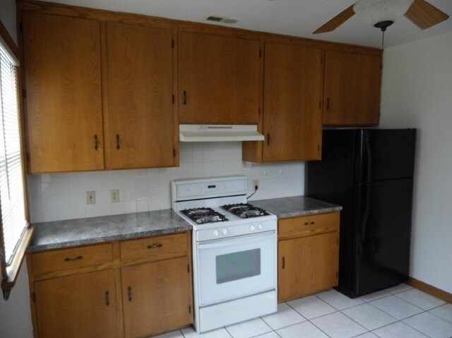 Gas stove and refrigerator is surrounded with floor to ceiling wood cupboards. - 742 E Ford Ave
