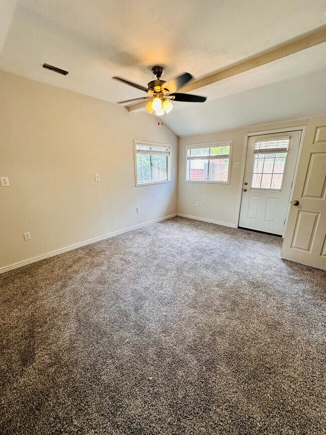Bright and inviting room with plush carpet, ceiling fan, and ample natural light from large windows and glass door. - 1385 Yukon Street