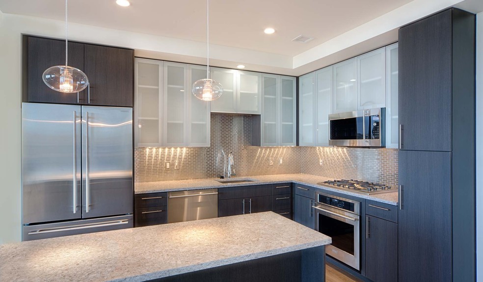 Penthouse kitchens feature frosted-glass cabinet doors, quartz countertops and breakfast bars - One Canal Apartments