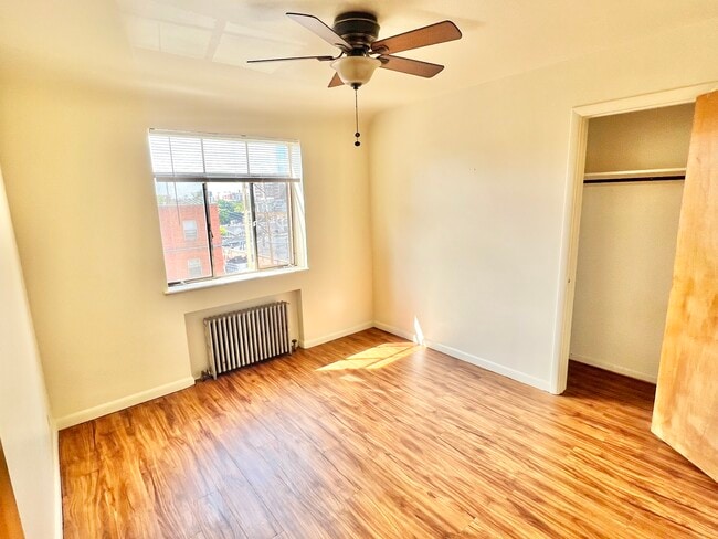 Bright and airy bedroom featuring elegant wooden floors and a serene view. - Hillside Apartments