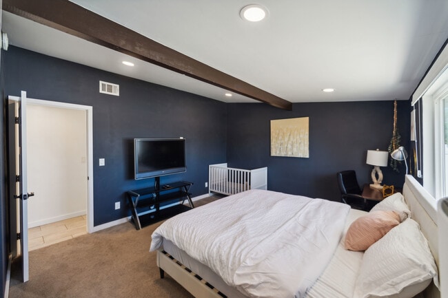 Enjoy a comfortable bedroom featuring a king bed, baby crib, workspace, and smart TV - 9853 Saint George St