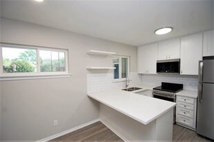 Kitchen with SS Appliances and Quartz Peninsula Countertops - Pine Village Boutique Apartments