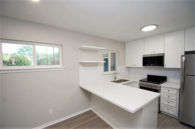 Kitchen with SS Appliances and Quartz Peninsula Countertops - Pine Village Boutique Apartments