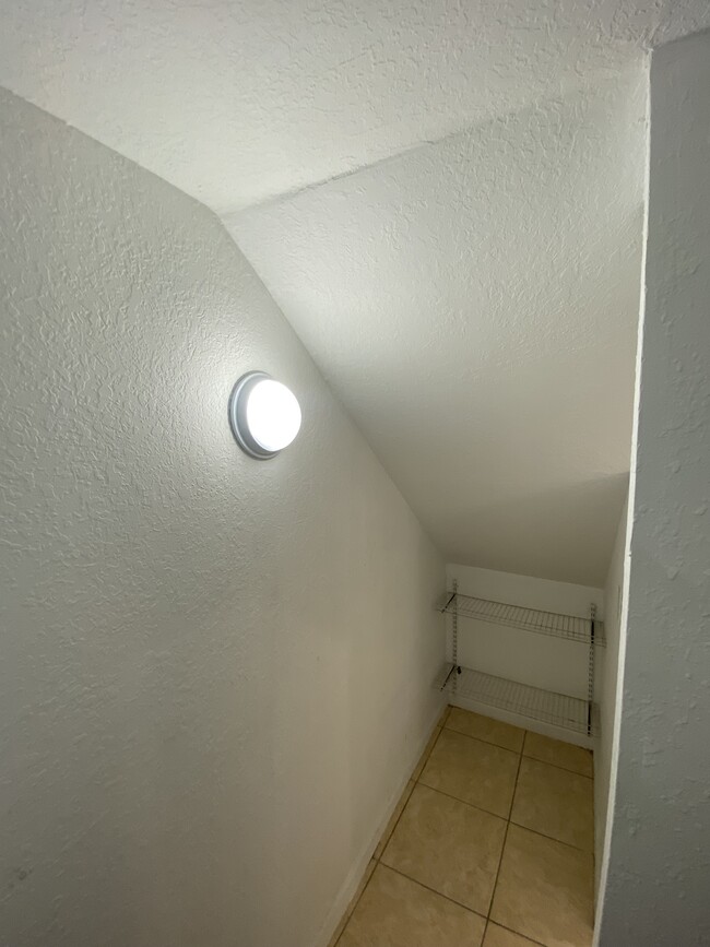 Spacious storage area under stairs with light for ease. - 2451 SE 14th Ave