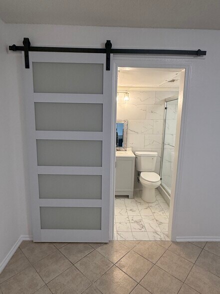 Barn door entry to bathroom. - 2301 Basil Dr