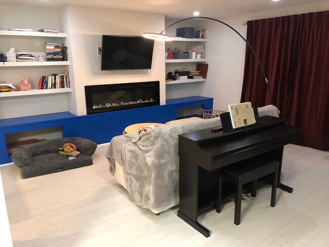 View of the living room shared between all tenants. SmartTV, electric fireplace, and digital piano. - 7922 Fitzroy St