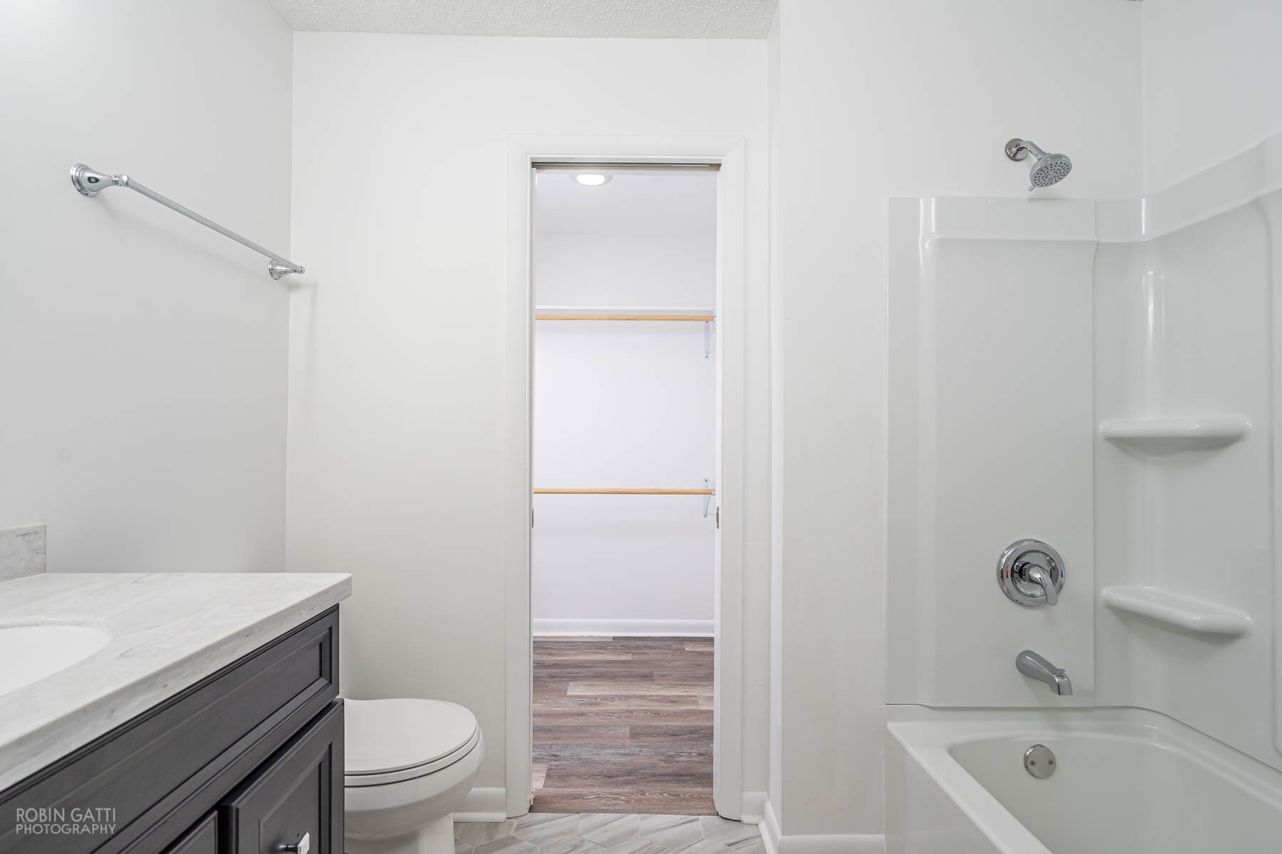 Master bathroom equipped with new tub/shower combo, tile, toilet, light fixtures, and vanity; walk-in closet entrance - 502 Cherokee Court