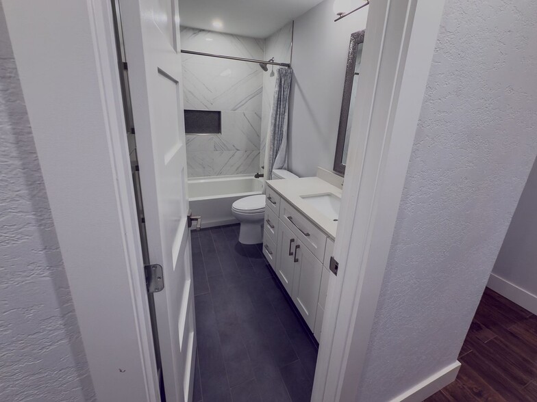 Updated bathroom with marble tile tub/shower surround and white vanity - 2006 Candle Ct