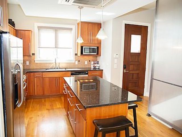 Image showing front door to the right and kitchen with stainless steel appliances and wood floors. - 300 Van Buren St