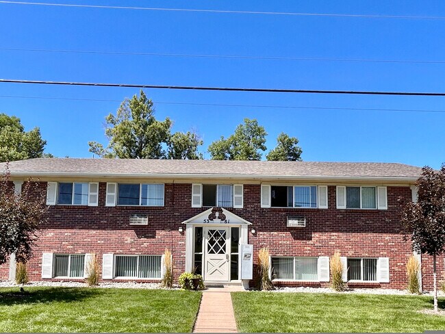 Brick apartment building with a well-maintained lawn, featuring a symmetrical design and multiple windows. - 5381 Delaware