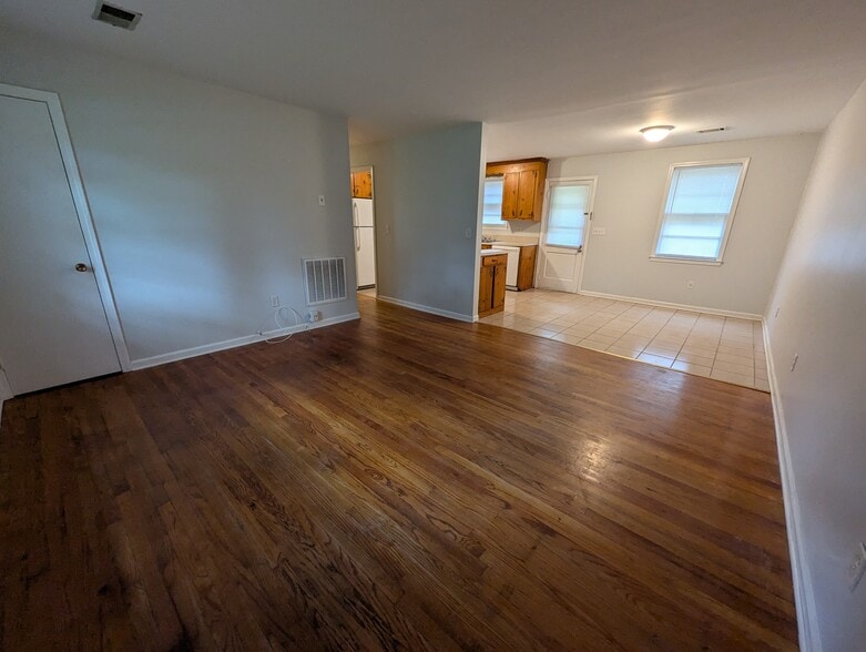 Spacious living and dining transition area highlighting warm hardwood floors and natural light. - 1527 Brookbank Ave