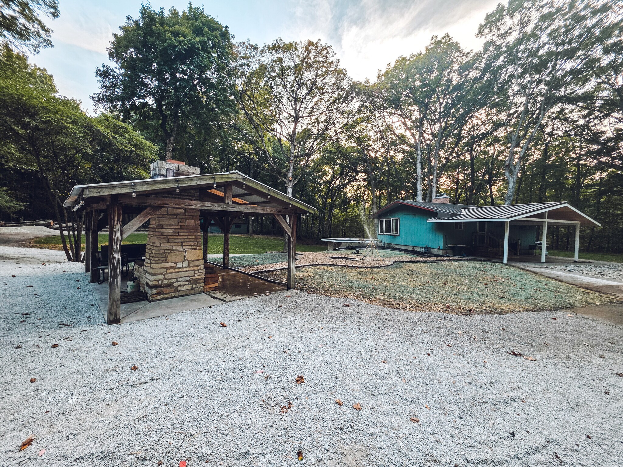The exterior includes an outdoor pavilion with fireplace and seating area and fire pit - 1008 W Singing Woods Rd