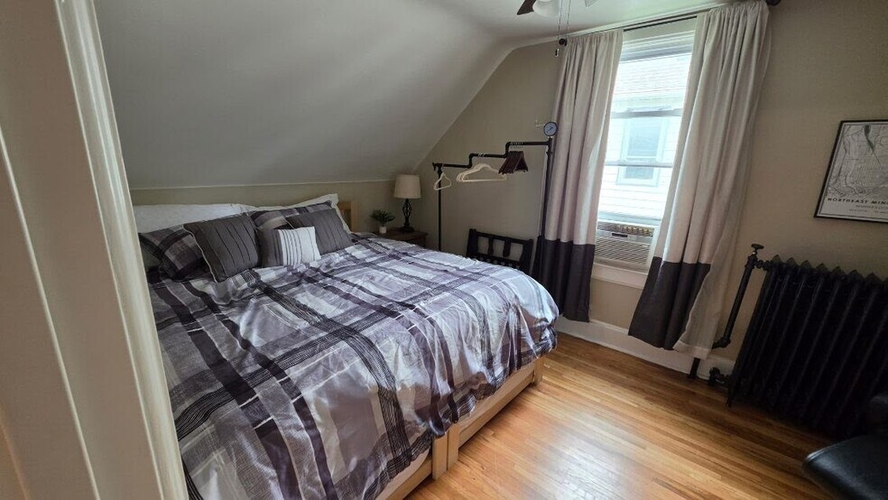 Comfortable king bedroom with hardwood floors and seasonal window AC. - 1901 -2301 Fillmore Street NE Minneapolis, MN 55418