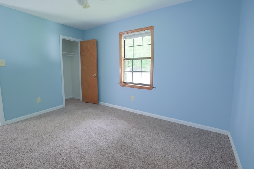 Bright guest bedroom with soft light, neutral carpet, and cheerful blue walls. - 2313 Salem West Dr