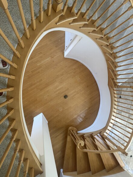 Elegant spiral staircase links entryway, lower-level entertainment, and upper suites - 8120 Billowvista Dr