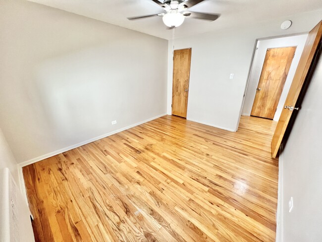 Embrace serenity in this bright bedroom featuring elegant hardwood flooring. - The Birney Apartments