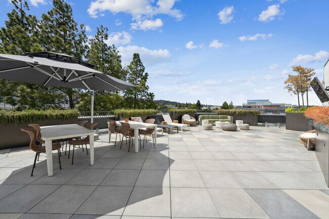 Chic rooftop terrace with stylish seating, spacious dining tables, and scenic views. - Akin Residences