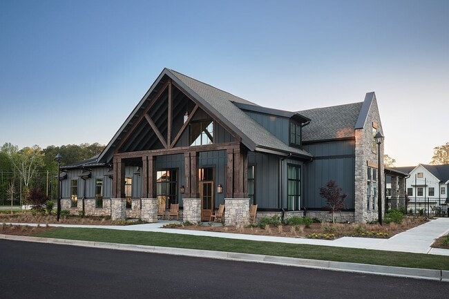 Clubhouse exterior with ample parking and rocking chairs on the front porch. - The Bend at Pettit Creek