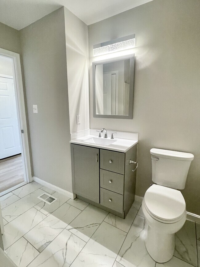 renovated guest bathroom with ceramic tile, new vanities, toilets, lights, and mirrors - 12430 Horseshoe Bend Cir