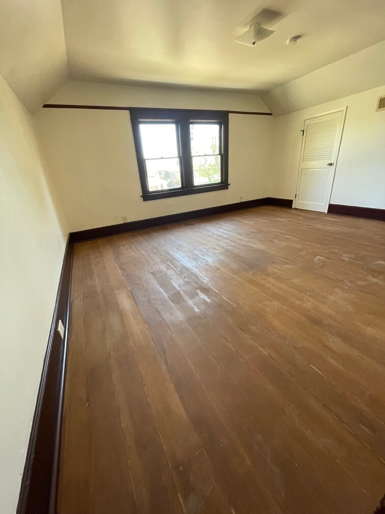 Fourth bedroom with a separate storage area through the light colored door. Restored hardwood floor - 1135 Magnolia St