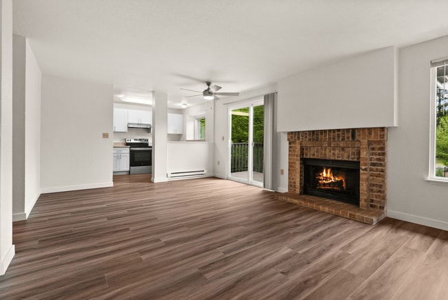 Enjoy the warmth of a classic brick fireplace and the charm of open-concept living in this beautifully updated apartment, complete with wood-style flooring and a modern kitchen. - Windemere Apartments