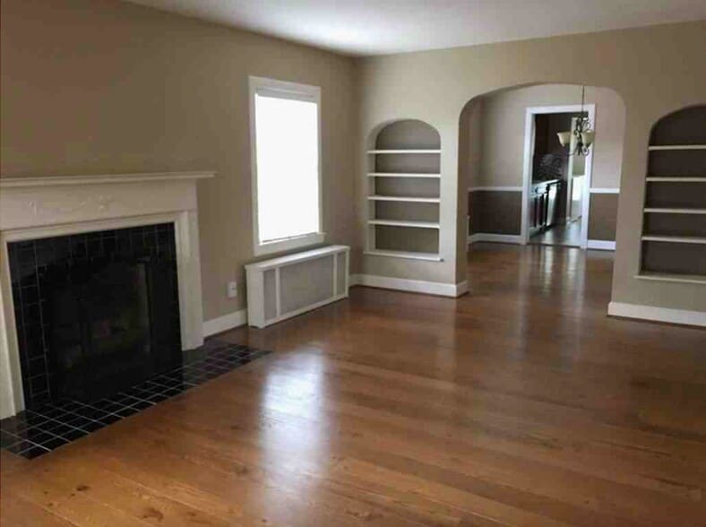 Large, bright, and welcoming living room with cozy gas fireplace, hardwood floors, original built-in shelves and open concept to dining and kitchen. - 2325 Broadmeade Road