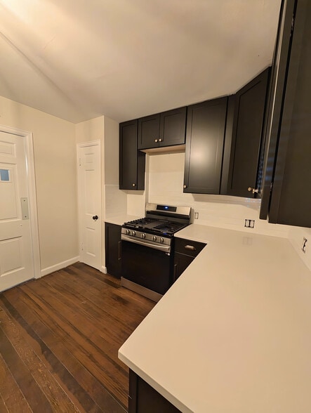 Renovated kitchen with gas stove, quartz counters and black cabinets. - 2734 N Avondale Blvd