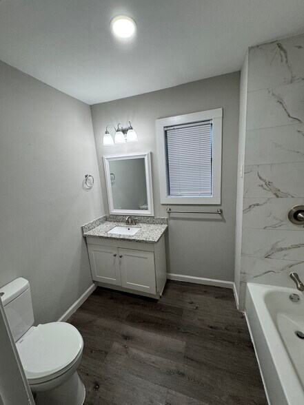 Clean and modern second bathroom featuring a white vanity with granite countertop. - 11927 Troulon Dr