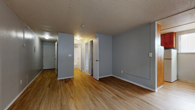 Inviting living space featuring warm wooden floors and abundant natural light. - Harmony Apartments