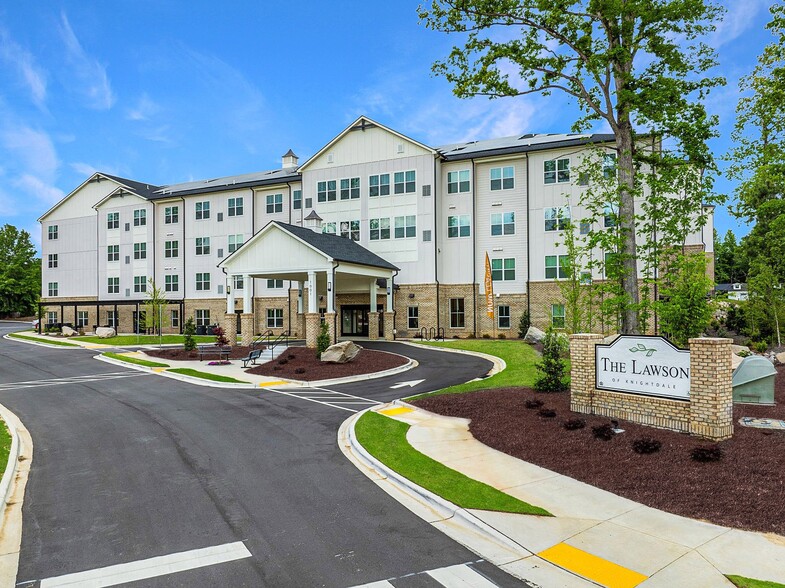 Active Adult Community with an exterior view of an apartment building with a courtyard and benches - The Lawson of Knightdale