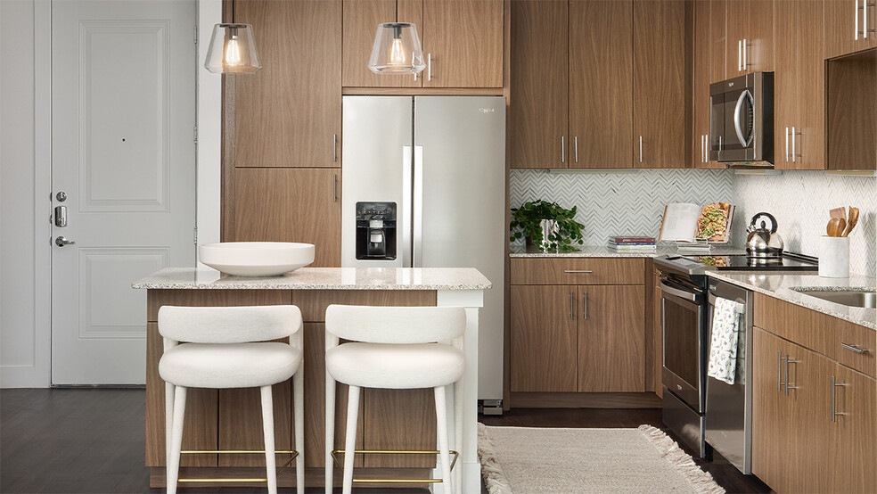 Apartment kitchen with stainless steel appliances, granite countertops, and wood-style flooring. - Griffis Oak Lawn