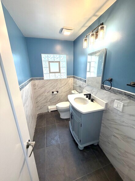 Beautifully redone 1/2 bath with new quartz vanity, Kohler toilet, tile & faucet. - 771 56th St