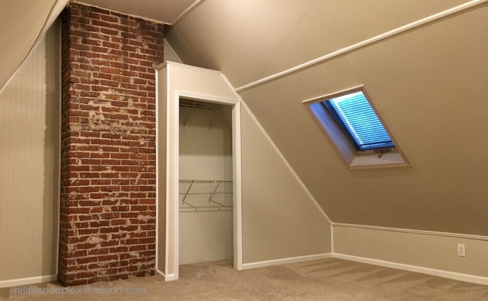 Main bedroom with vaulted ceiling and skylight. - 629 Hillpine Dr NE