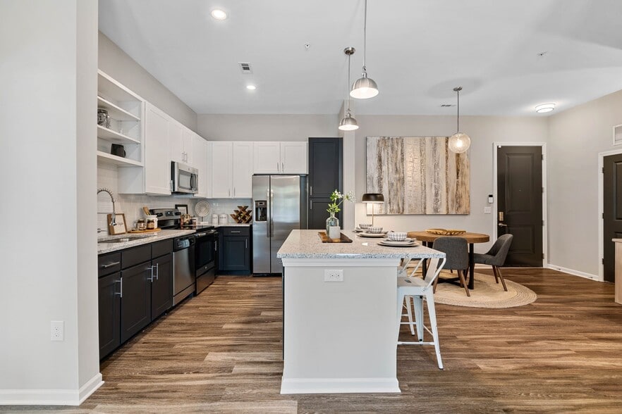 Kitchen with white and dark cabinetry, speckled granite countertops, white subway tile backsplash, stainless steel appliances, and hard surface flooring - Avalon at Palisades