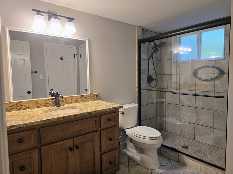 Primary ensuite bath with granite vanity, large walk-in shower and gorgeous Travertine tile - 90 Martin Point Ct