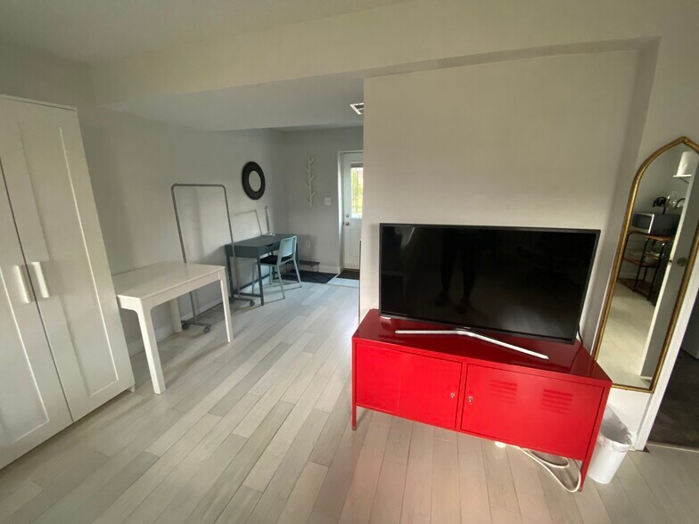 View of the TV and TV stand in the basement unit. - 7922 Fitzroy St
