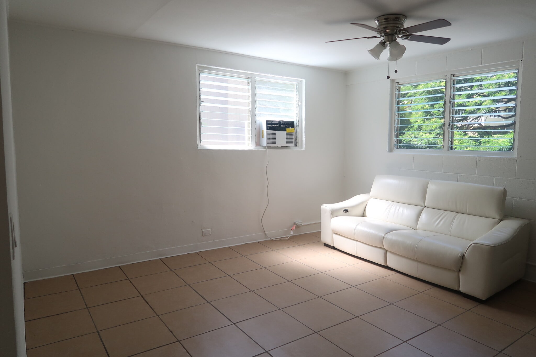 Large living room, furnished with electric reclining leather couch, and AC - 1739 Kamohoalii St