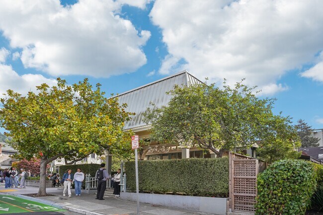 Group of people standing outside of a building with trees - 2605 Haste Street